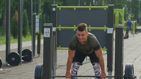 Man lifting weights at an outdoor gym Stock Footage 100034108