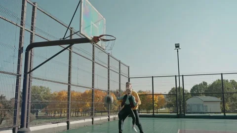 Man lifts his son to throw the ball into the ring on a court on a sunny day Vídeo Stock 166836618