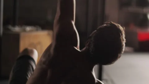 Man lifts kettlebell overhead while performing dynamic gym exercise Stock Footage 312764191