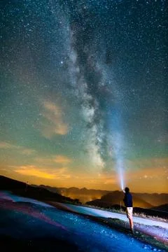 Man with a light standing at night with milky way Stock Photos
