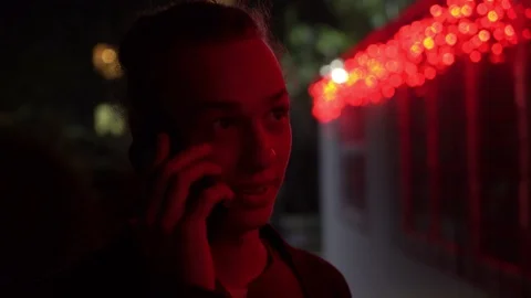 Man lighted of red light talking on the phone on the street at night 1 Video stock 95905736