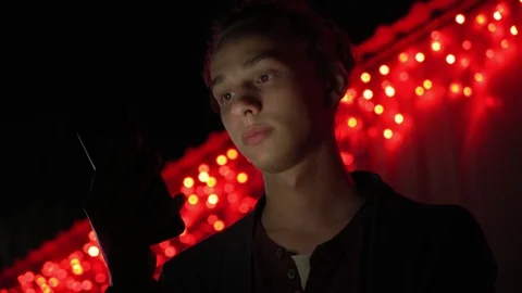 Man lighted of red light use smartphone on the street at night 9 Video stock 95861958