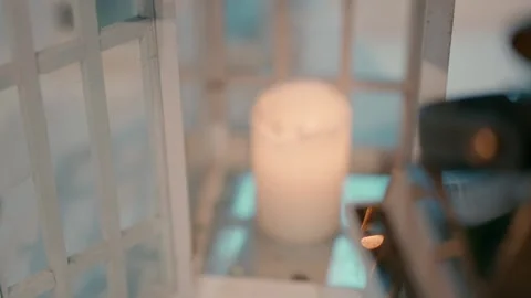 A man lighting a candle and putting it in a white vintage style lamp. Stock Footage 230156722