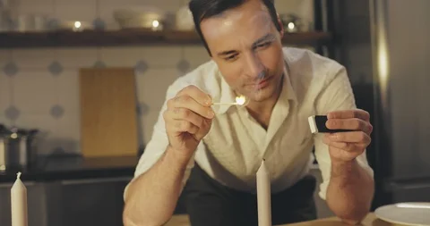 Man lighting candles in kitchen Stock Footage 114119978