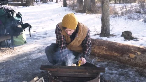 Man lighting fire in firepit in snowy forest Stock Footage 221033111
