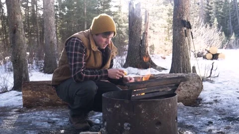 Man lighting fire in firepit in snowy forest Stock Footage 221033140