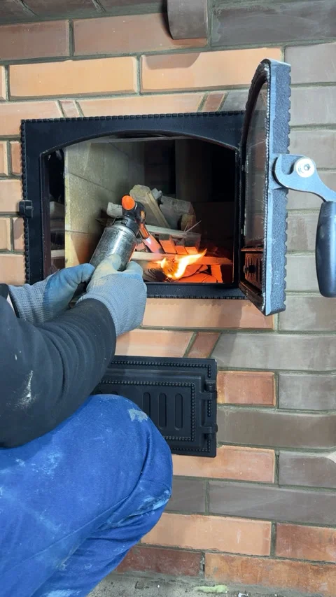 A man lighting a fire in a stove firebox. A test fire ignition in a new sto.. 動画素材 327606099