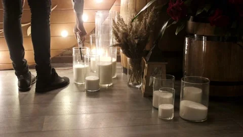 Man lights bulk candles on the floor. Preparing for a wedding or holiday. Stock Footage 197983413