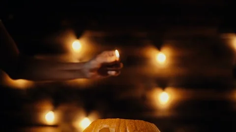 Man lights a candle inside a Halloween pumpkin with a match in dark room. Video stock 117567066