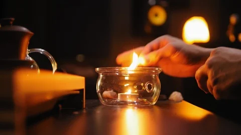 A man lights a candle with a match and puts the kettle on the fire. Stock Footage 107729809