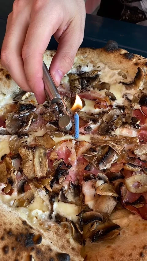 A man lights a candle in a pizza with a lighter. Holiday. Birthday. Video stock 342002124
