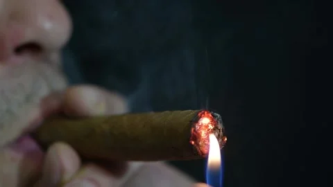 A man lights a cigar from a lighter on a dark background, close-up, selective fo Stock Footage 165291633