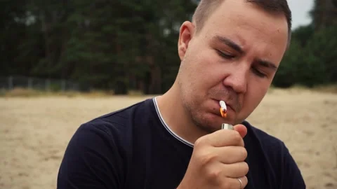 Man lights a cigarette on the beach. 4k footage Video stock 164092448