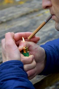 A man lights a cigarette from a lighter in the Stock Photos
