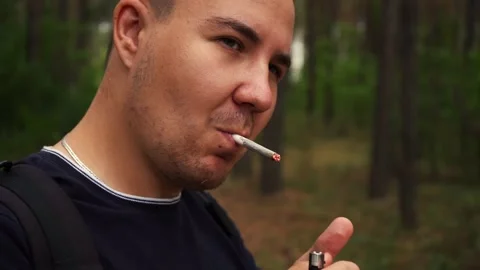 Man lights a cigarette while in the woods Stock Footage 158896111