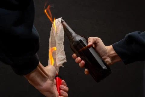 A man lights a cloth in a bottle, igniting a molotov cocktail. Stock Photos