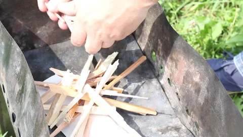 A man lights a fire on the grill. Burns match paper and wood chips. Close-up  Stock Footage 134974879