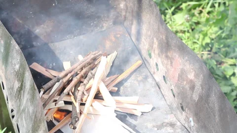 A man lights a fire on the grill. Lays wood chips and brushwood on burning pa Stock Footage 134974961