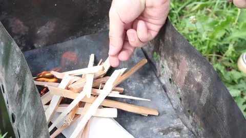 A man lights a fire on the grill. Lays wood chips on burning paper. Close-up  Stock Footage 134975036