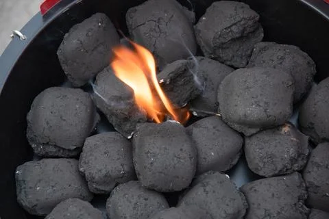 A man lights a fire with a lighter special charcoals for a barbecue Stock Photos