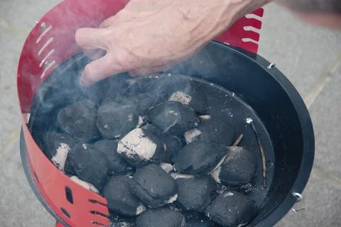 A man lights a fire with a lighter special charcoals for a barbecue Stock Photos