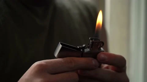 Man lights a gasoline lighter while sitting in a room Stock Footage 164063628