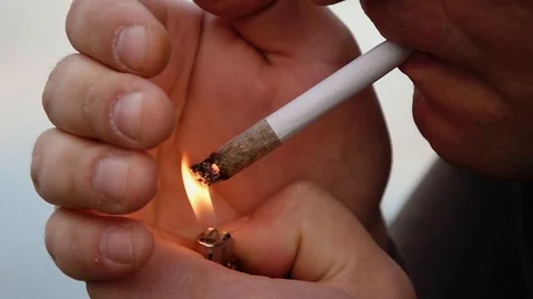A man lights a joint with his hand covering the fire, close-up. Stock Footage 129109089
