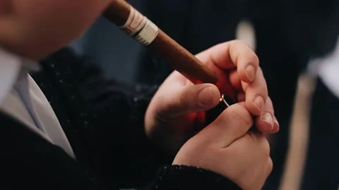 A man lights a large cigar while holding it in his hands. Close-up shooting. Stock Footage 156052543