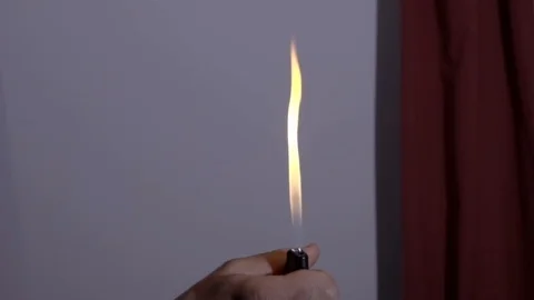 Man lights large flame with cigarette lighter in room, close-up Stockbeeldmateriaal 106120804