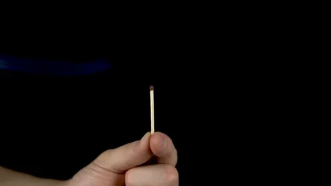 A man lights a match from the fire. A man holds a match in his hand and lights Stockbeeldmateriaal 123314552