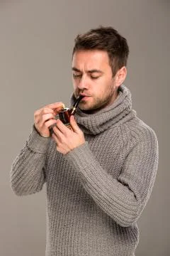 Man lights a pipe Stock Photos