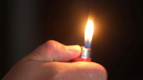 A man lights a red cigarette lighter lighter Stock Footage 156697100