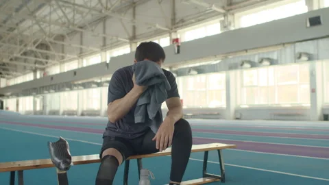 Man with Limb Prosthesis Wiping off Sweat after Indoor Training Stock Footage 259286322