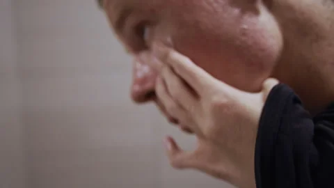 Man with Limited Hand Mobility Applying Face Cream in Bathroom 库存影片 321942623