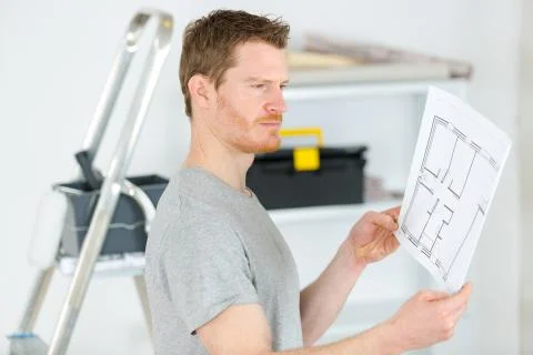 Man lin room ooking at floorplan Stock Photos