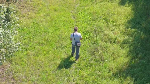 A man in linen pants and a light shirt strolls with his dog through fields .. Stock Footage 283722082