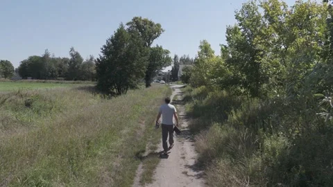 A man in linen pants and a light shirt walks with his dog through fields an.. Stock Footage 283722269