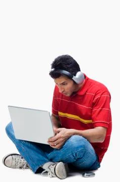 Man listening to headphones while using a laptop Stock-Fotos