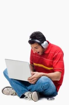 Man listening to headphones while using a laptop 写真素材
