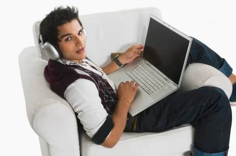 Man listening to headphones while using a laptop Stock Photos