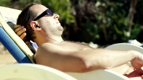 Man Listening to mp3 player during sunbathing 스톡 동영상 1068778