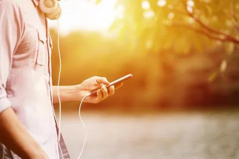 A Man listening to a music from a smartphone with garden background Stock Photos