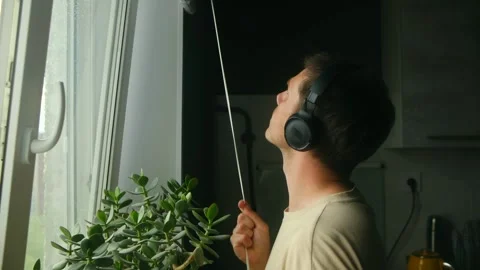 Man listening to music while opening blinds in kitchen Video stock 313642972