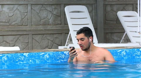 Man listens to music in the pool 스톡 동영상 64986982
