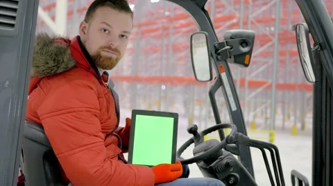 Man in loader, presses on the tablet with a green screen and smile at camera at Video stock 61315630