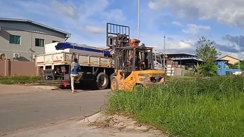 Man loading building materials with a forklift assisted by two men Stock Footage 304610391