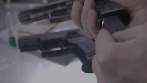 Man loading bullets into gun, close-up of hands CSI Vidéo 86445374