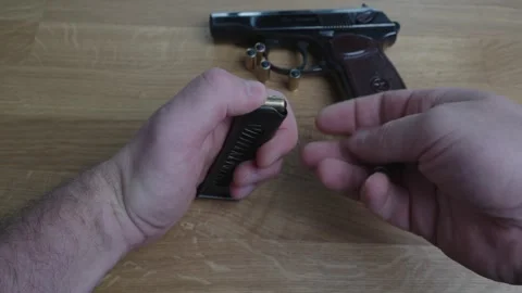 Man Loading Bullets into Pistol Magazine Near Handgun on Table Stock Footage 340405515