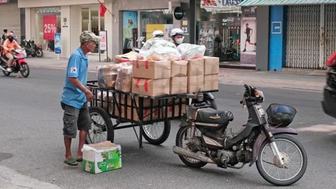 Man Loading Cargo Onto a Motorbike Trailer on a Busy Street 動画素材 338404833