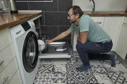 Man loading dishwasher in modern kitchen Stock Photos